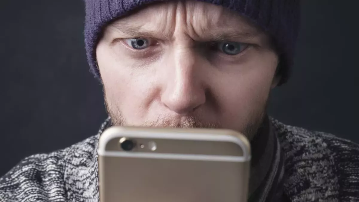 Un homme regardant son smartphone avec surprise (illustration).