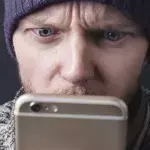 Un homme regardant son smartphone avec surprise (illustration).